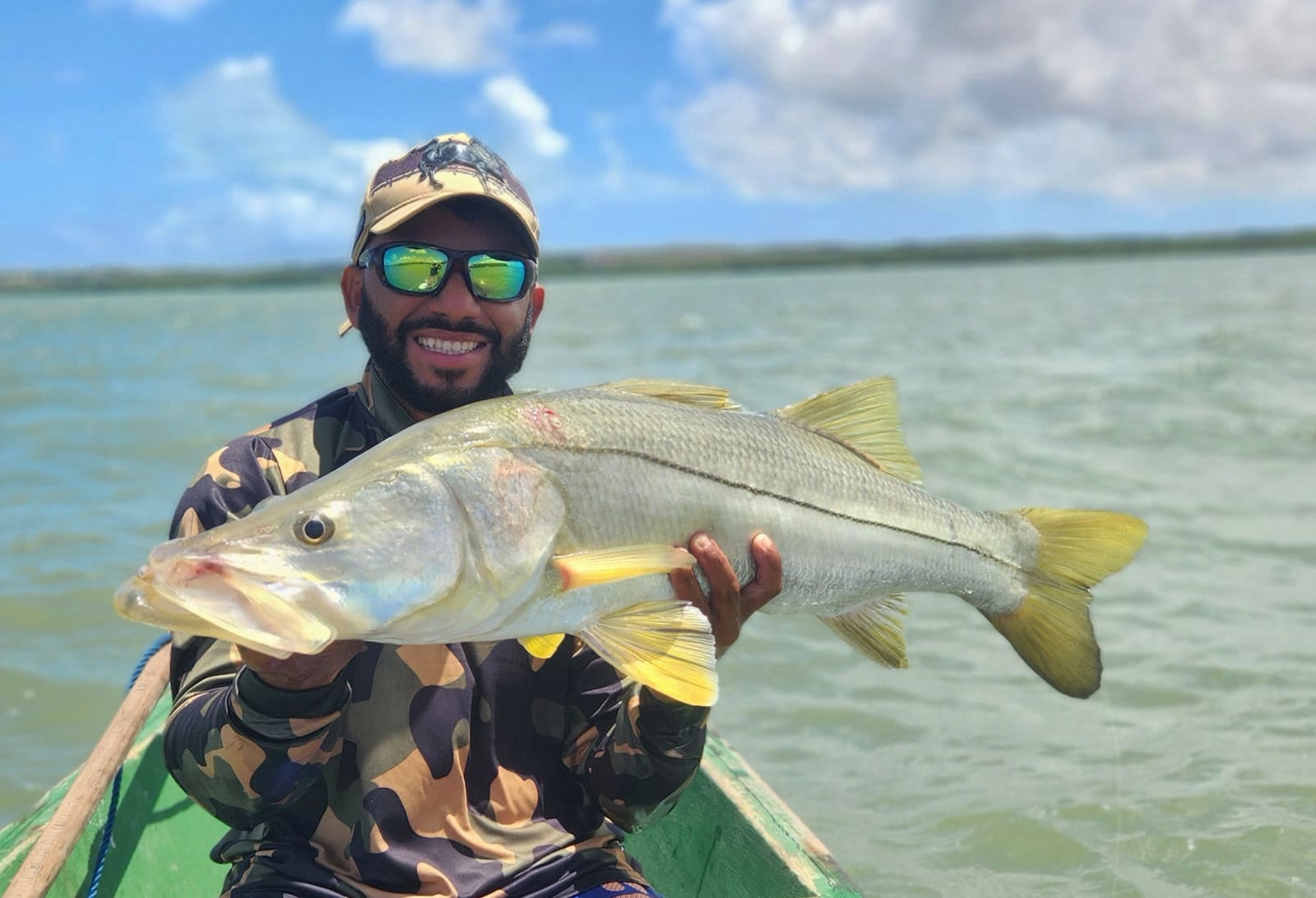 Pescador sorrindo com um robalo grande no barco